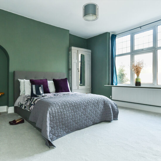 Elegant-bedroom-with-green-colour-palette-comfortable-bed-and-soft-glow-lighting-emma-martin-interiors-nottingham